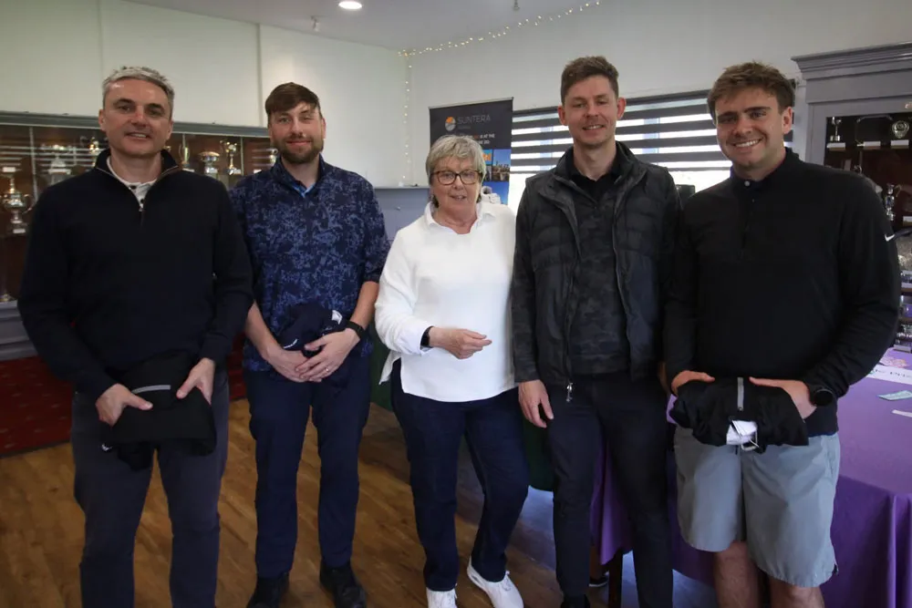 The players from the Cannaccord Genuity team are being presented with their prizes by Janet Henthorn in the clubhouse. All are smiling for the camera.